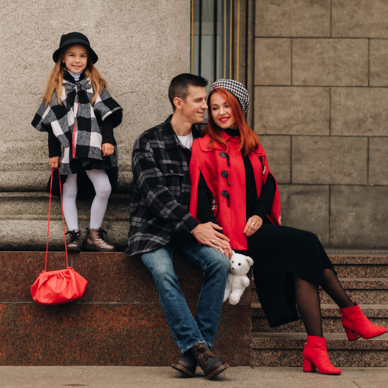 A stylish family of three strolls through the autumn city posing for a photographer . Dad, mom and daughter in the autumn city.